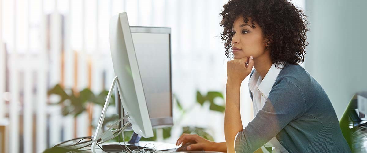 woman facing a dual screen office desk.