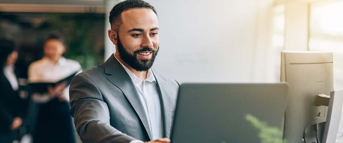  man working on a laptop with people in the background.