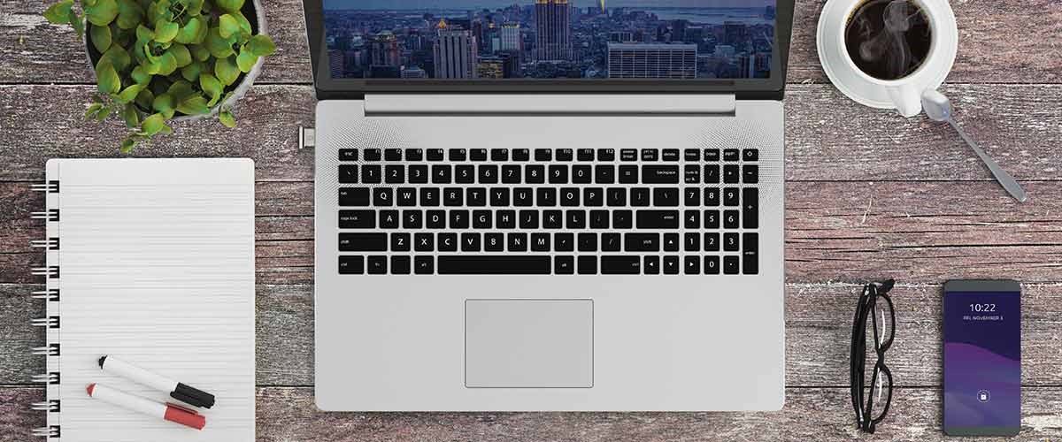 Windows Hello Laptop  with a Kensington VeriMark Guard biometric key on a wooden table.