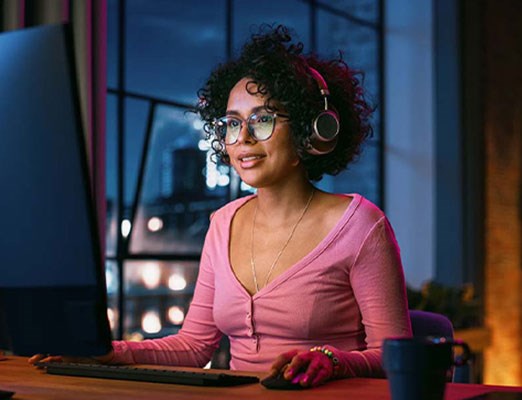 woman working at a computer with bright lights and headphones.