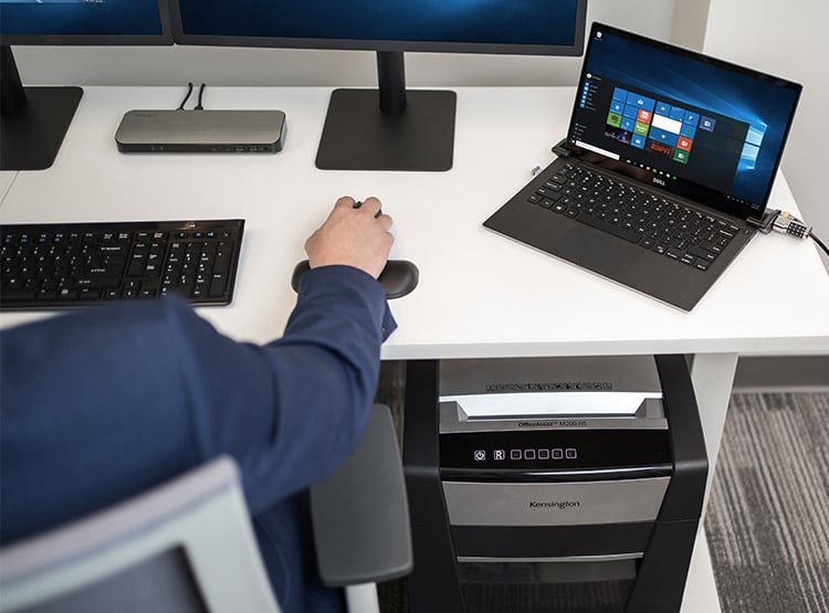 Man sitting working at his desk with a Kensington shredder underneath it.