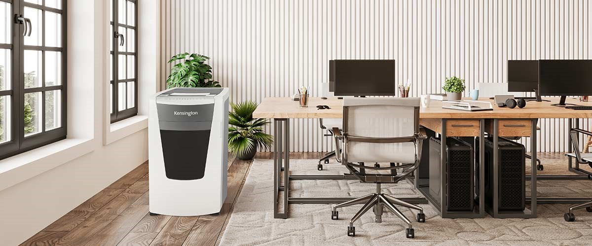 Desks with a Kensington shredder on the side in a minimalist office.
