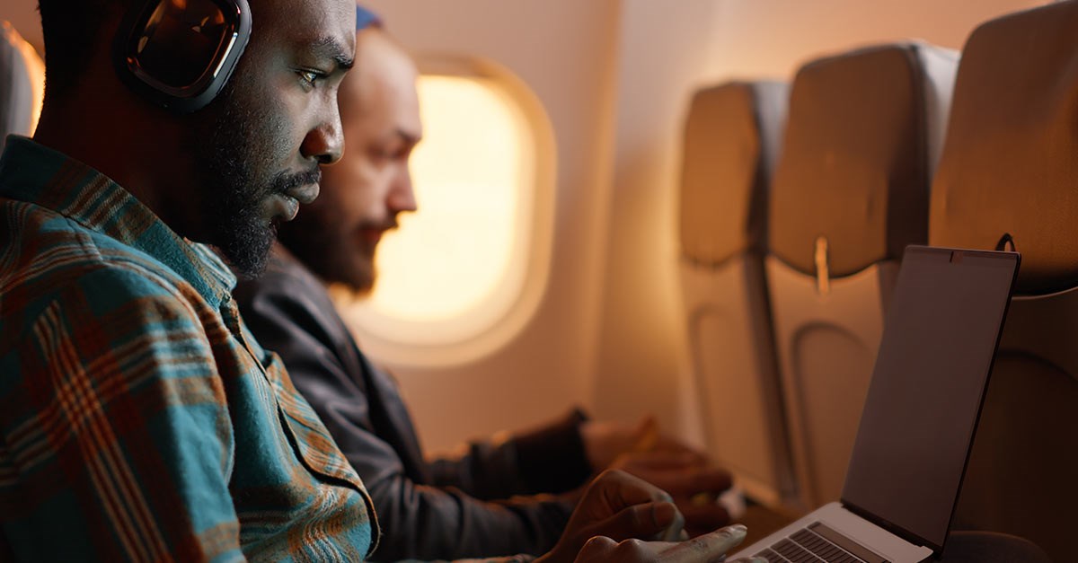 A man working during a flight and using a privacy screen to protect his data and screen.