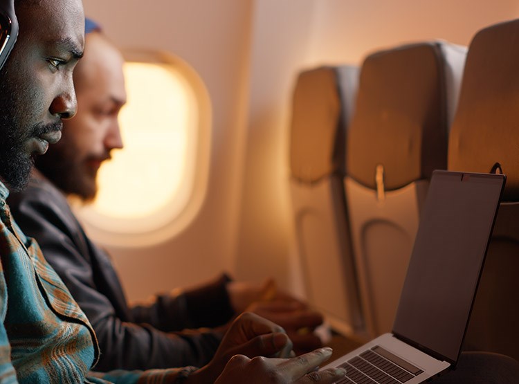 A man working during a flight and using a privacy screen to protect his data and screen.