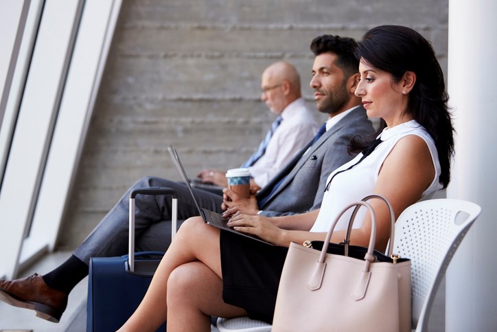 A business professional sitting at the airport departure lounge and working on their laptop.