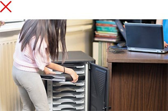 Woman using a Kensington charging station with a cluttered environment.