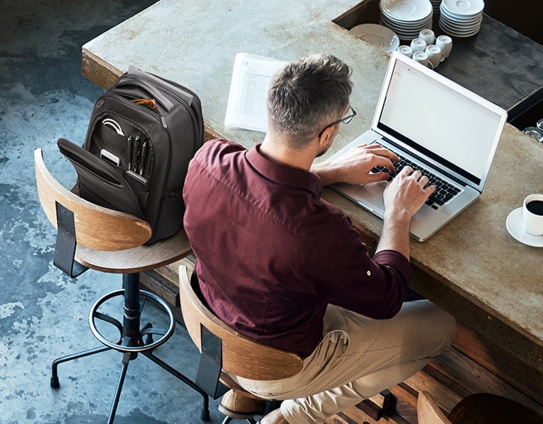 Man workin from a coffee shop using kensington products.