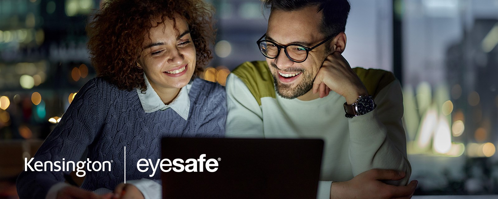 A man and woman looking at a laptop that has a Kensington eyesafe privacy screen covering the screen.