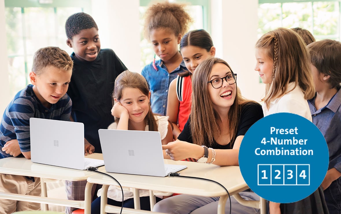 Eine junge Lehrerin unterrichtet einige Kinder mit Laptops, die mit einem Serienschloss gesichert sind.