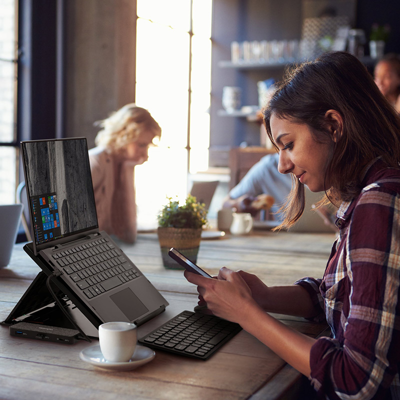 Woman working at cafe with Kensington laptop riser