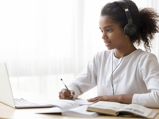 Young woman doing schoolwork with a Kensington headset