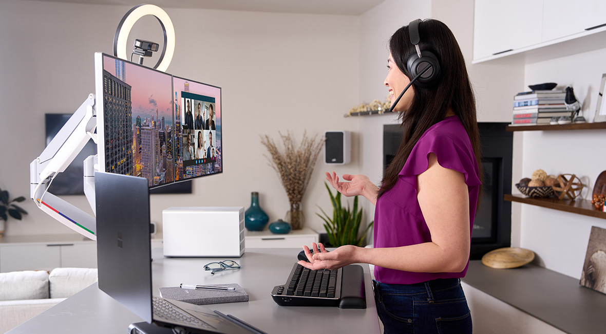 Woman standing while working at her desk using Kensington video conferencing accessories