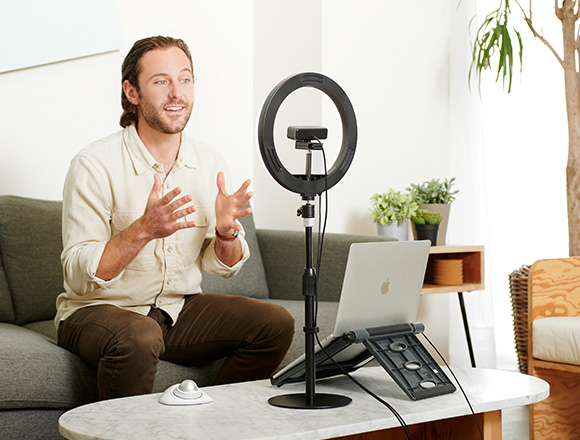 Man on a couch using a Kensington Ring Light and Webcam