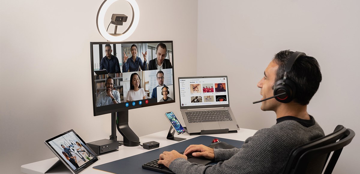 Man with headset using Kensington Audio Switch while video conferencing and working on his laptop