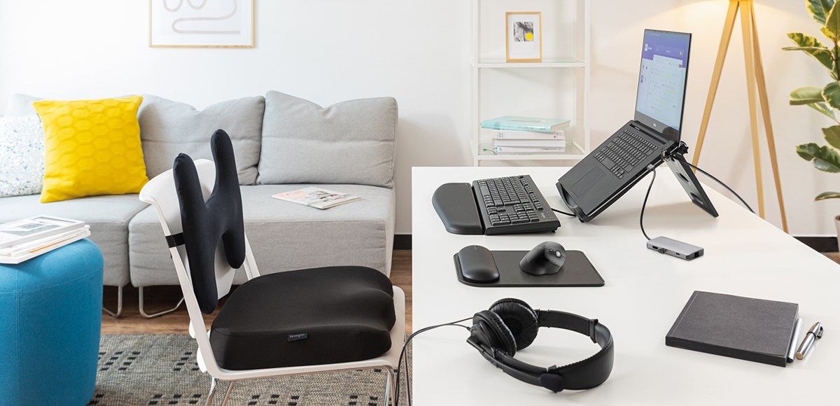 Home office desk set up equipped with a laptop riser, mouse pad, key board and a back rest