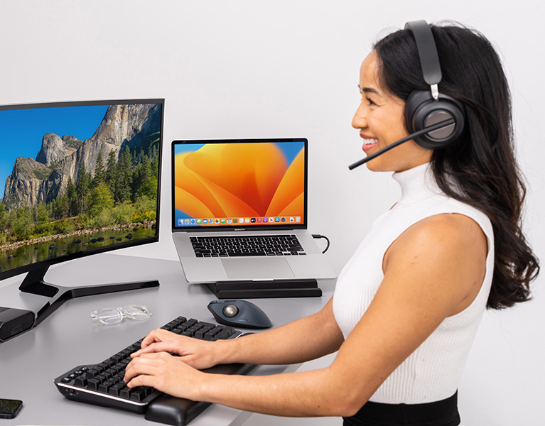 Woman setting up her desktop with Kensington Pro Video Conferencing products.