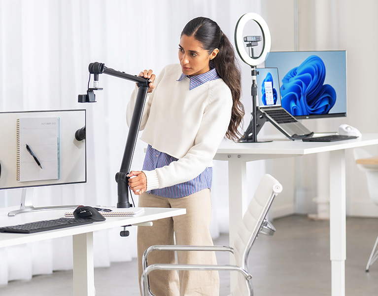 Woman setting up her desktop with Kensington Pro Video Conferencing products