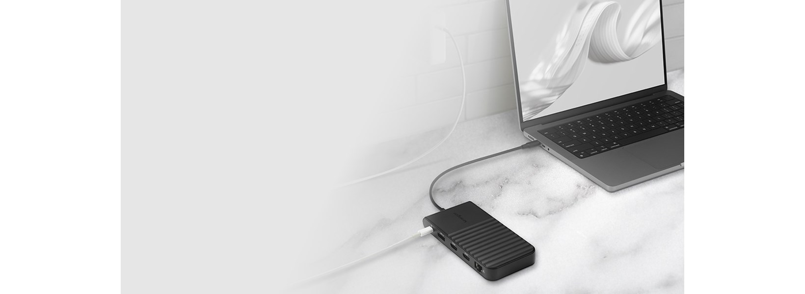 Laptop connected to a docking station on a marble surface.