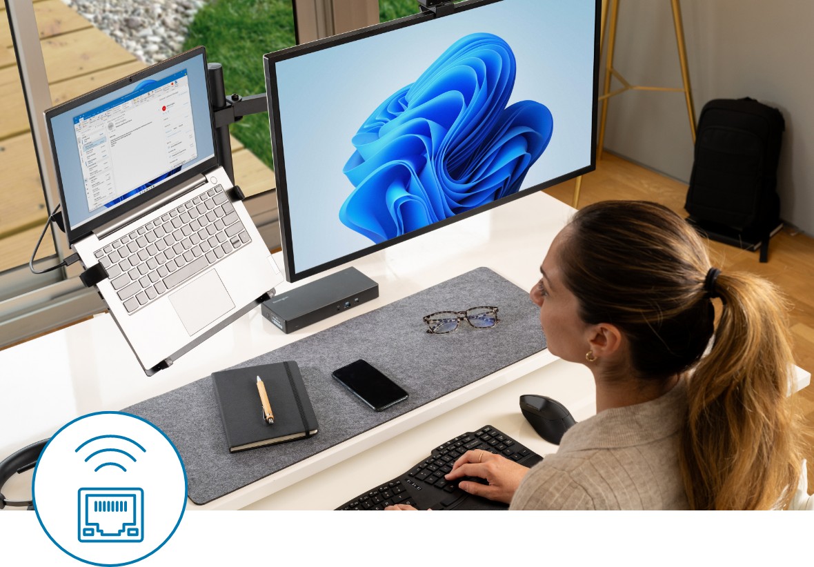 Mujer escribiendo un correo electrónico en su ordenador mientras una segunda pantalla está conectada a través de un replicador de puertos de Kensington.