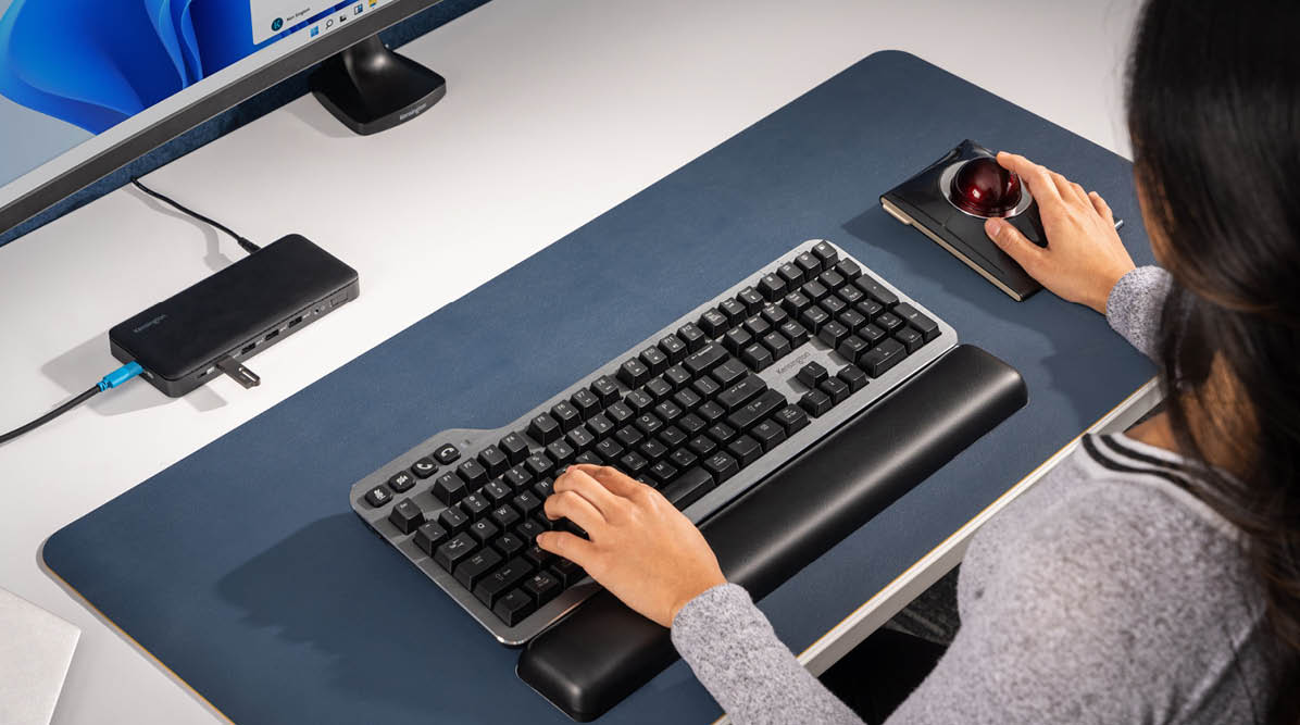 Woman working at a desk using a Kensington Mechanical Keyboard and Trackball