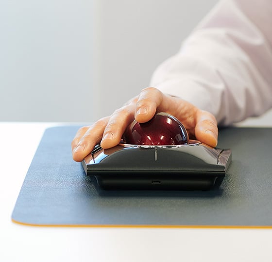 Close up of a professional using a Kensington SlimBlade™ Pro Trackball on a mousepad.