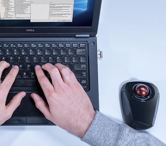 Person typing on laptop with trackball