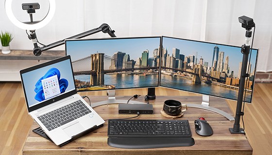 A desk with a central desktop docking station that connects a laptop to multiple devices.