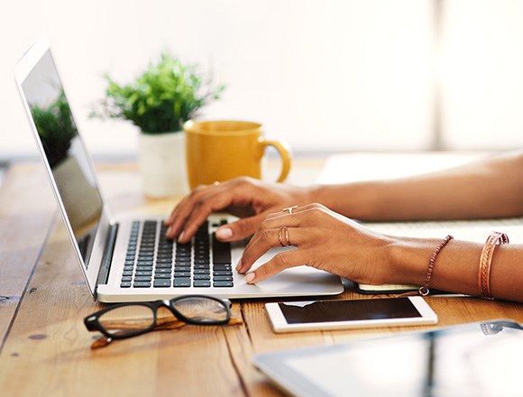 a person typing on a laptop, presumably writing a blog.