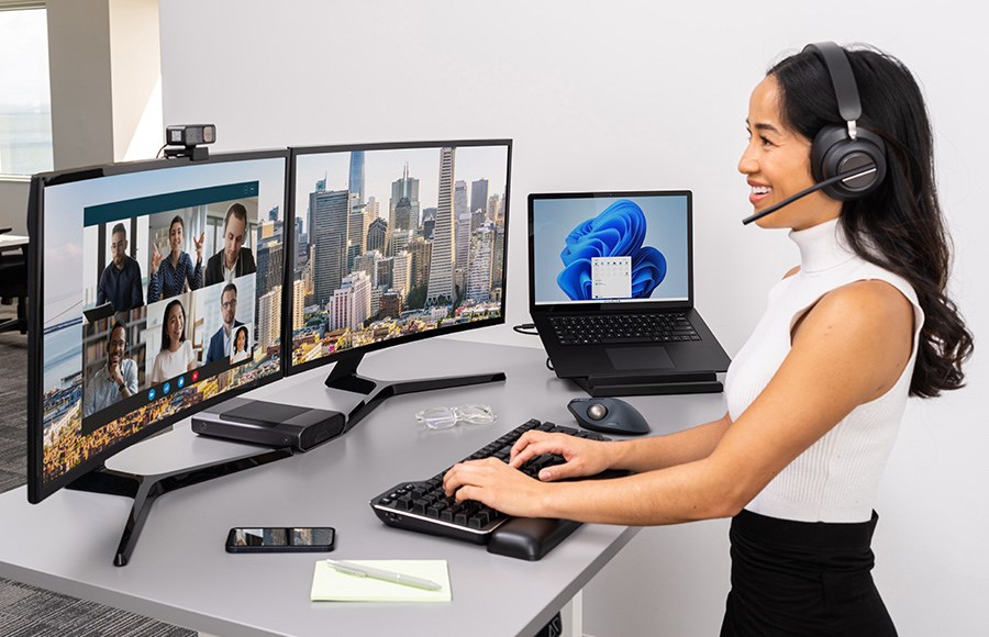 Una mujer en una videollamada usa una docking station para conectar su notebook a varios dispositivos.