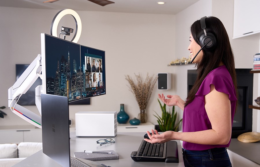 A woman working from home in conference call using a docking station to connect multiple devices.