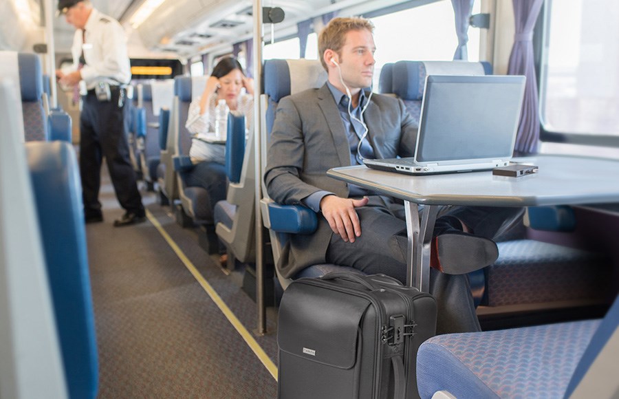 一名商务人士在火车上，他的笔记本电脑连接在移动扩展坞上。