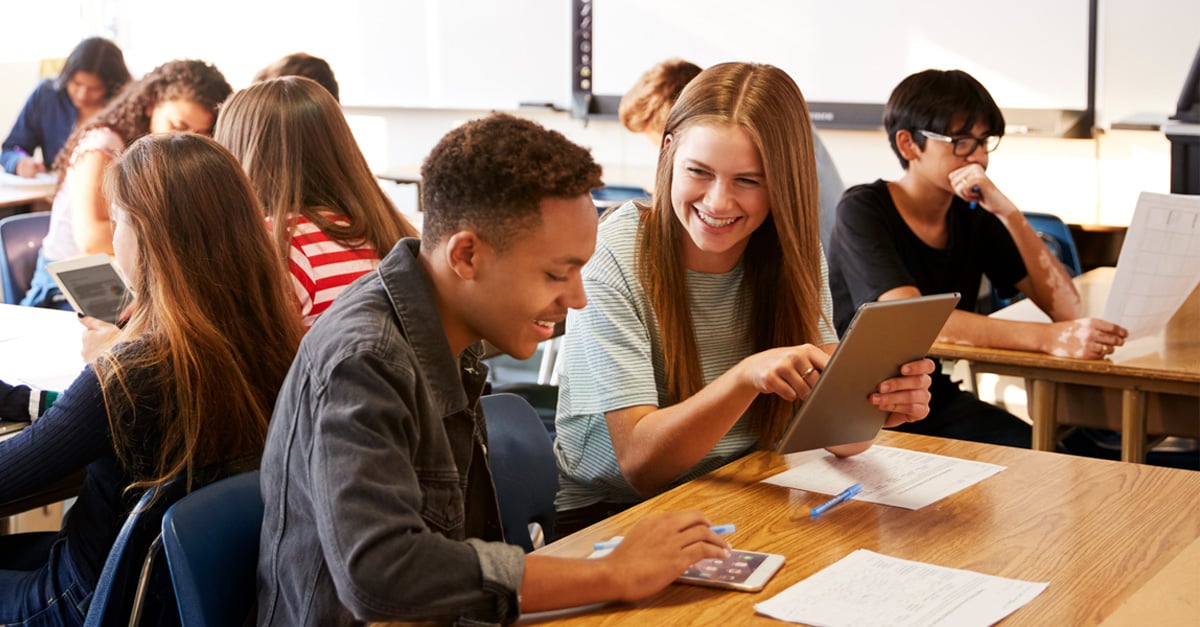 A teacher helping a student at the student's desk