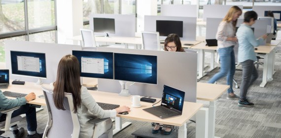 men and women working on computers and talking in shared workspace