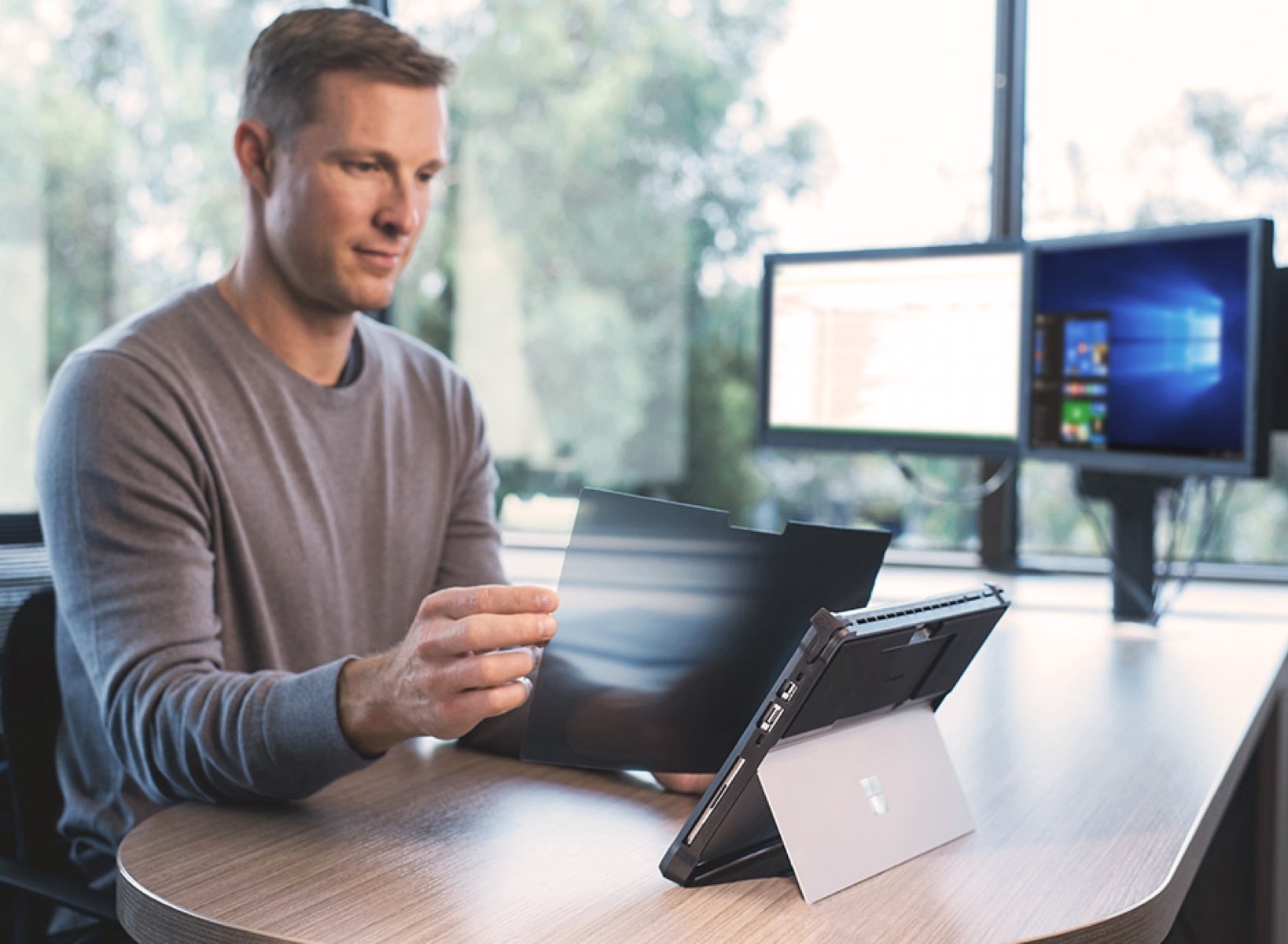 Man putting on a screen protector on his microsoft tablet.