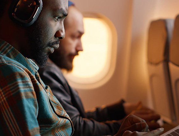 Blog: Two men on airplane using Kensington MagPro Magnetic and Direct Attach Privacy Screens on devices. 