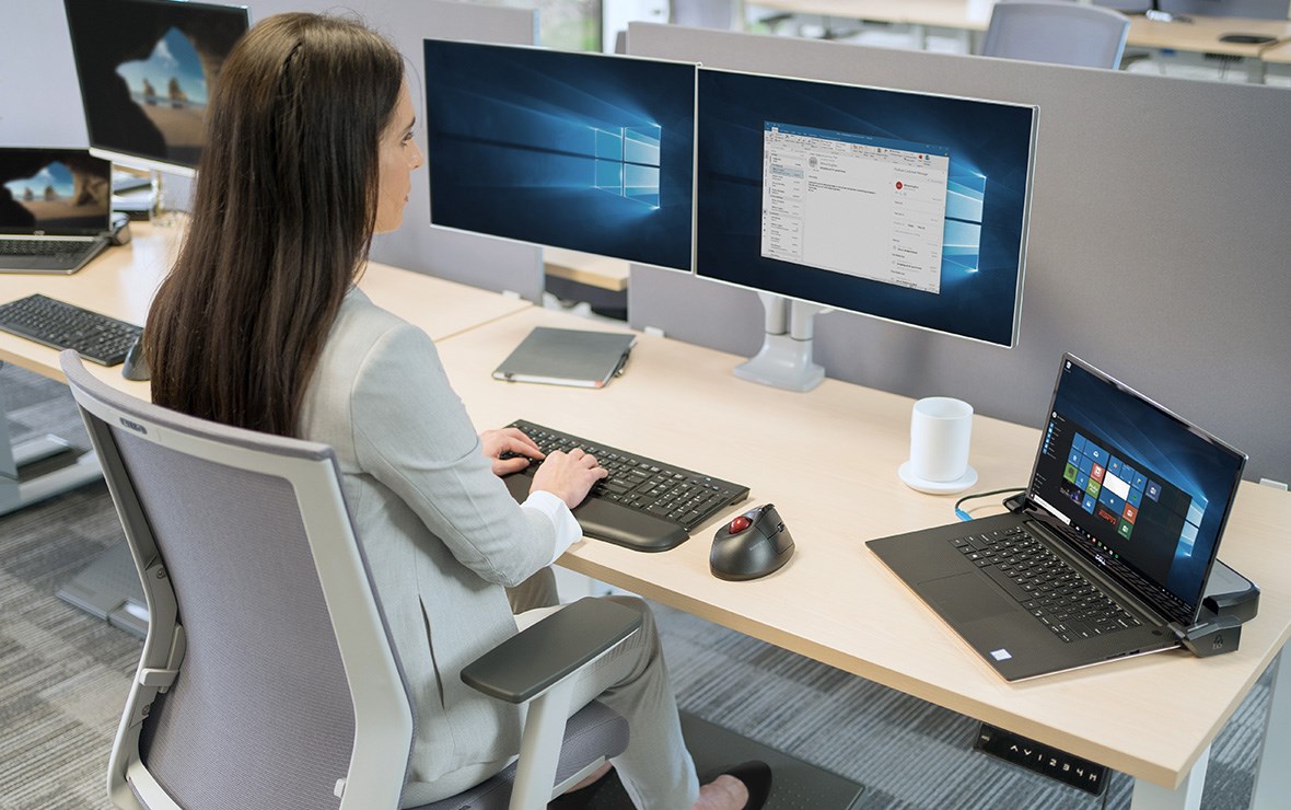 Woman working at the office and, several Kensington products on her desk.